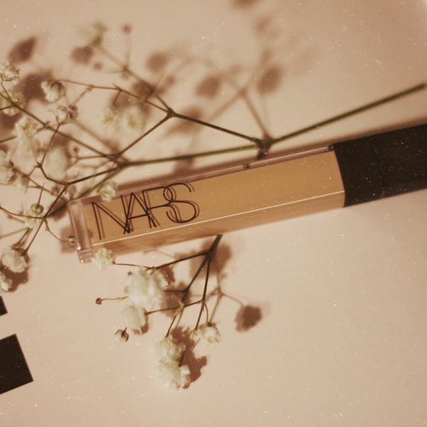 Concealer tube beside sprigs of dried white flowers